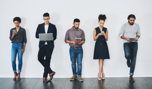 Young professional people standing against a white wall using technology.