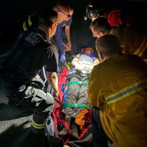 First responder surround rescued paraglider on a stretcher. 
