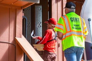CERT and Search and Rescue Volunteers knocking on a resident's door with evacuation orders.
