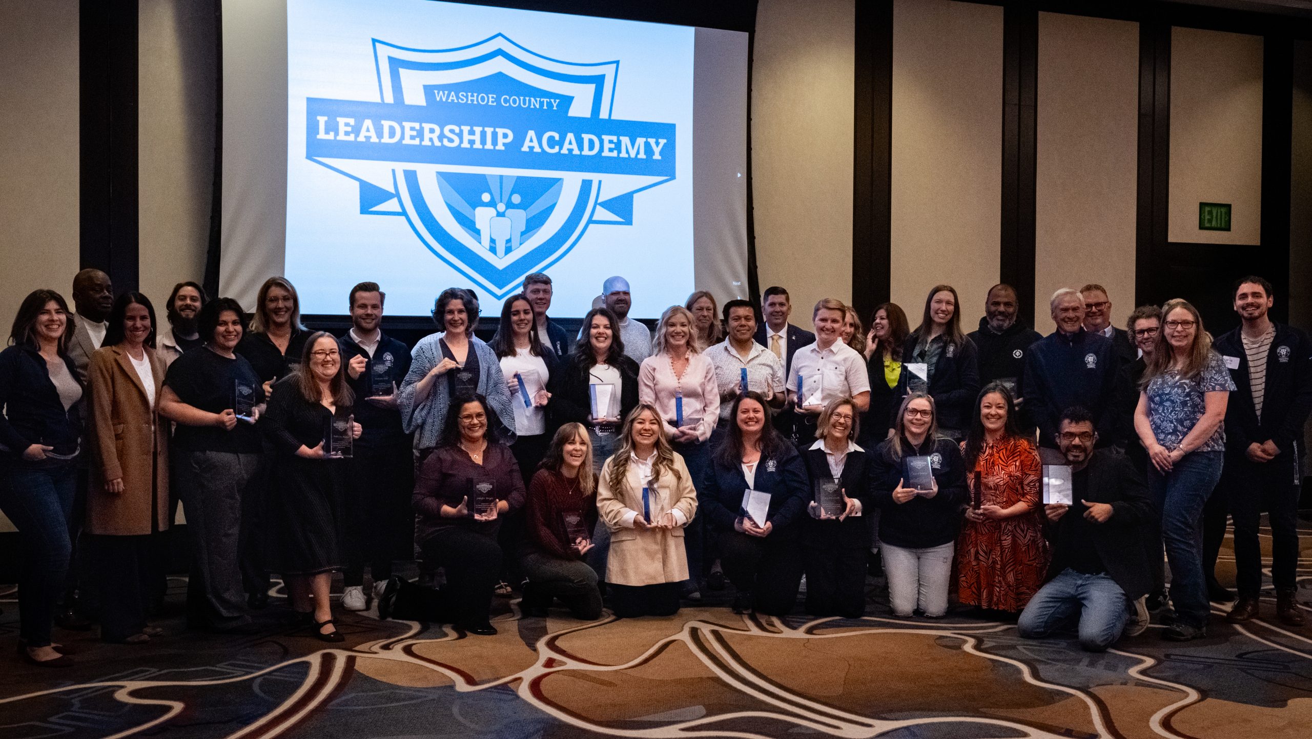 Photo of a large group of people posing in front of a Washoe County Leadership Academy logo