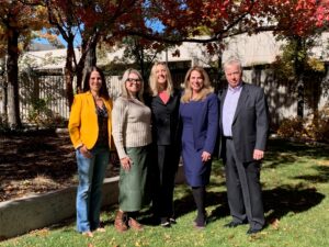 photo of five people posing for the camera outdoors.