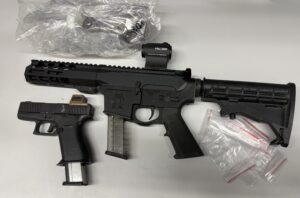 Photo of 2 illegal firearms. Black rifle and a black pistol with an extended magazine.