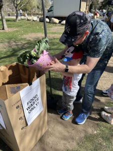 Father and young son putting food waste into a collection bin 