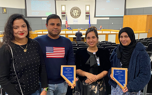 four people holding awards for the Extra Mile Award from NNPH.